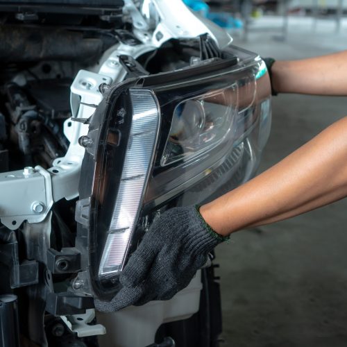 Mechanic with new car headlight in a workshop